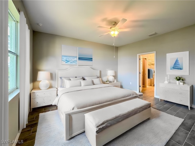 bedroom featuring dark wood-type flooring, multiple windows, a walk in closet, and ceiling fan