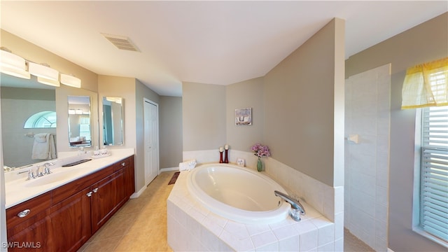 bathroom with tile patterned flooring, tiled bath, and vanity