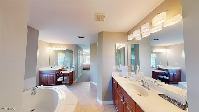 bathroom featuring tiled tub, vanity, and tile patterned flooring