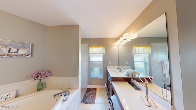 bathroom featuring tiled tub, vanity, tile patterned floors, and a wealth of natural light