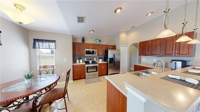 kitchen with pendant lighting, sink, lofted ceiling, stainless steel appliances, and backsplash