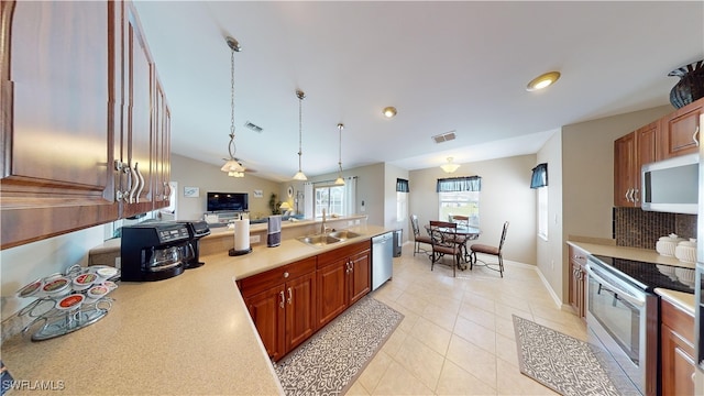 kitchen with light tile patterned flooring, vaulted ceiling, hanging light fixtures, stainless steel appliances, and backsplash