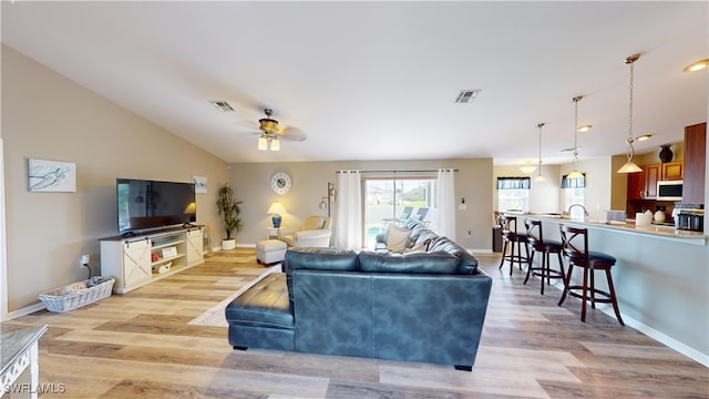 living room featuring ceiling fan, vaulted ceiling, and light hardwood / wood-style floors