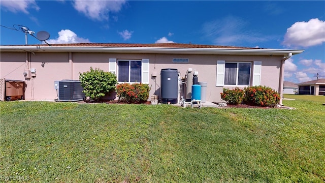 rear view of property featuring central AC unit and a lawn