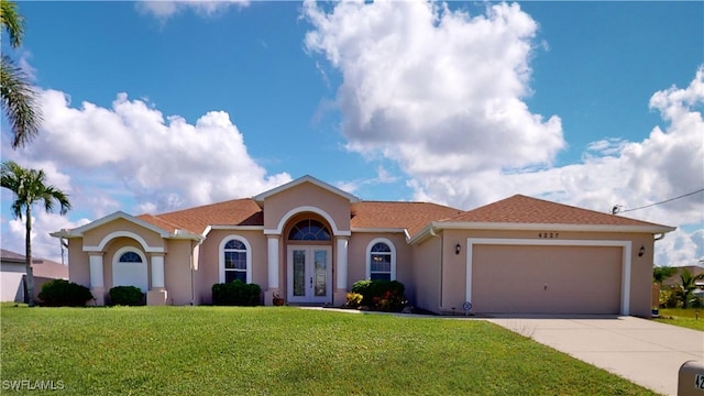 view of front of house featuring french doors, a garage, and a front lawn