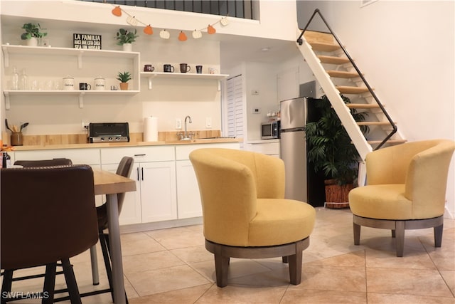 kitchen with white cabinetry, stainless steel appliances, and light tile patterned floors