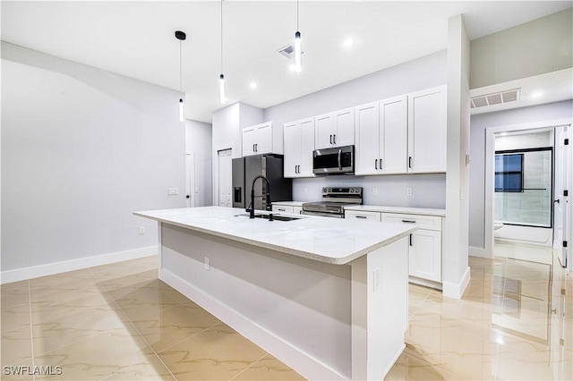 kitchen with pendant lighting, white cabinetry, stainless steel appliances, and a kitchen island with sink