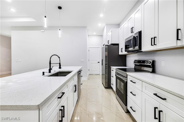 kitchen with stainless steel appliances, sink, decorative light fixtures, a center island with sink, and white cabinetry