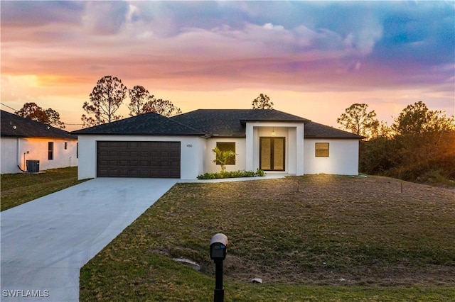 view of front of property with central AC unit, a garage, and a lawn