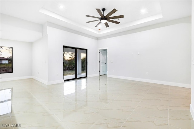 empty room with ceiling fan, a raised ceiling, and a towering ceiling