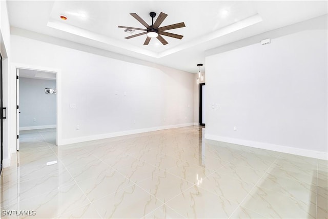 unfurnished room with ceiling fan and a tray ceiling