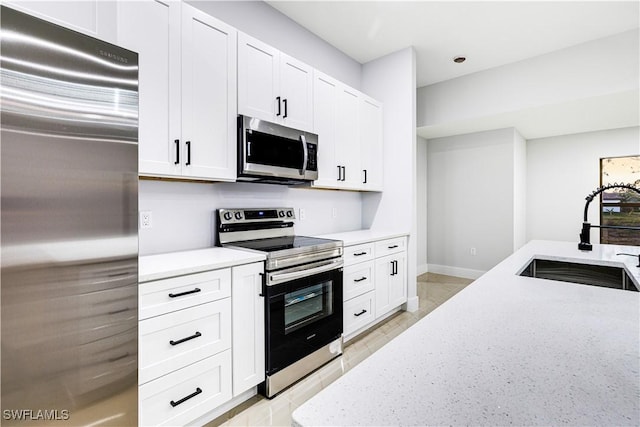 kitchen with light stone counters, sink, white cabinets, and appliances with stainless steel finishes