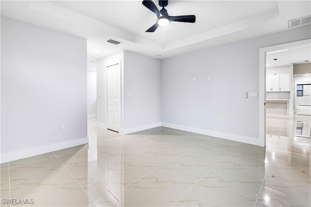 spare room with ceiling fan and a tray ceiling