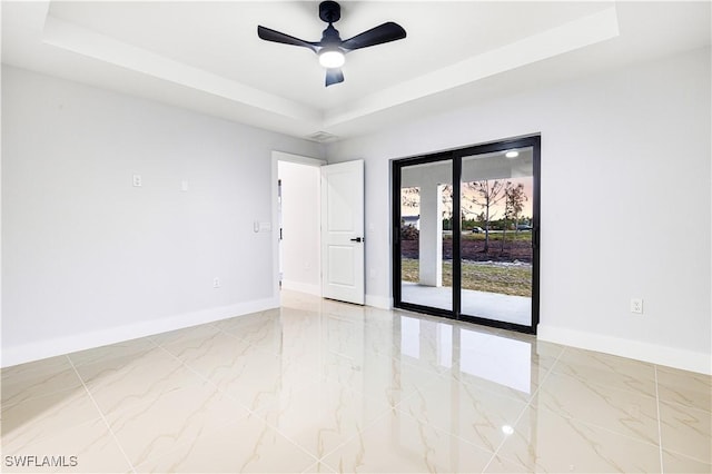 empty room with a raised ceiling and ceiling fan