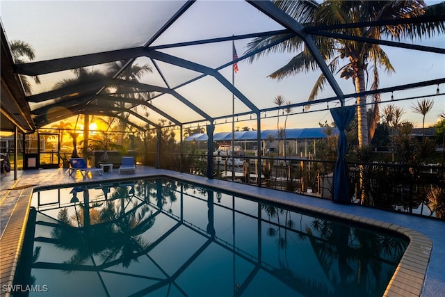 pool at dusk featuring a patio and a lanai