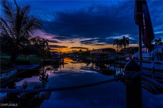 pool at dusk with a water view and a dock