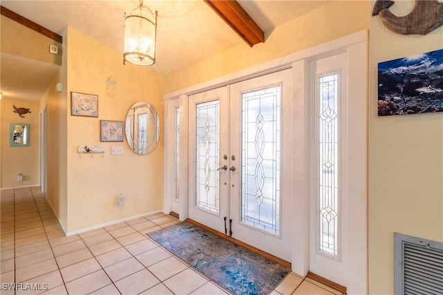 tiled foyer featuring a wealth of natural light, french doors, lofted ceiling with beams, and a notable chandelier