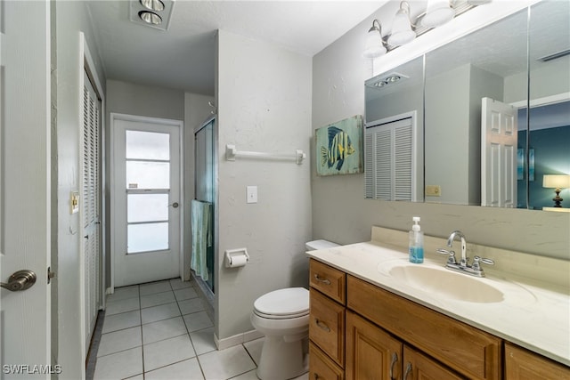 bathroom featuring vanity, walk in shower, toilet, and tile patterned floors