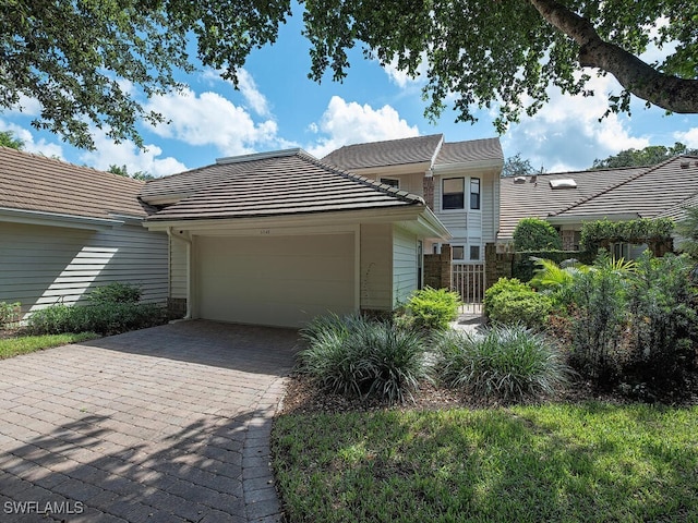 view of front of house featuring decorative driveway, a tile roof, fence, and an attached garage