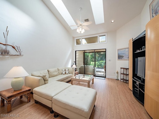 living room with a skylight, visible vents, light wood-style flooring, a ceiling fan, and high vaulted ceiling