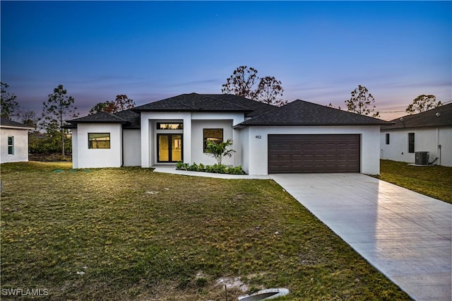 view of front of home featuring central AC unit, a garage, a lawn, and french doors