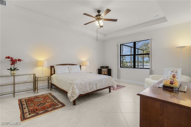 tiled bedroom featuring ceiling fan and a tray ceiling