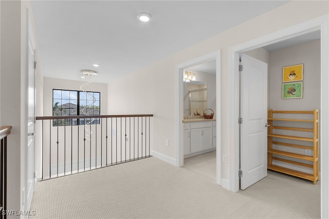 hallway featuring light carpet and a chandelier