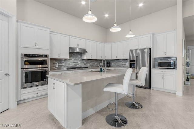 kitchen with sink, stainless steel appliances, a kitchen breakfast bar, an island with sink, and white cabinets