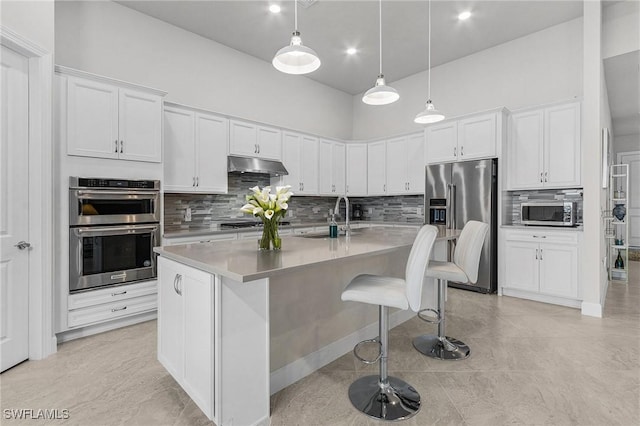 kitchen featuring white cabinetry, sink, an island with sink, a breakfast bar, and appliances with stainless steel finishes