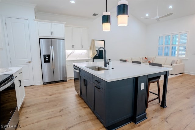 kitchen with decorative light fixtures, light hardwood / wood-style floors, stainless steel appliances, and sink