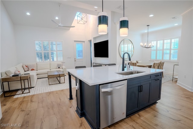 kitchen featuring hanging light fixtures, stainless steel dishwasher, sink, and an island with sink