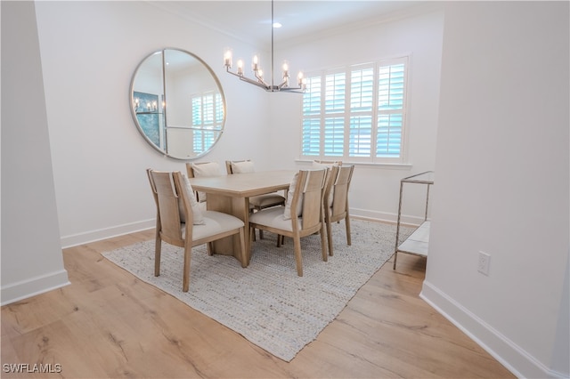 dining area featuring crown molding, light hardwood / wood-style floors, and an inviting chandelier