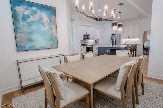 dining area featuring a chandelier, light hardwood / wood-style floors, and sink