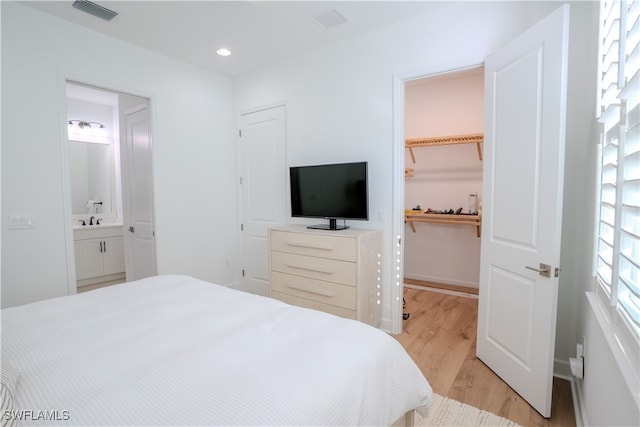 bedroom featuring sink, light hardwood / wood-style flooring, a closet, a spacious closet, and ensuite bathroom