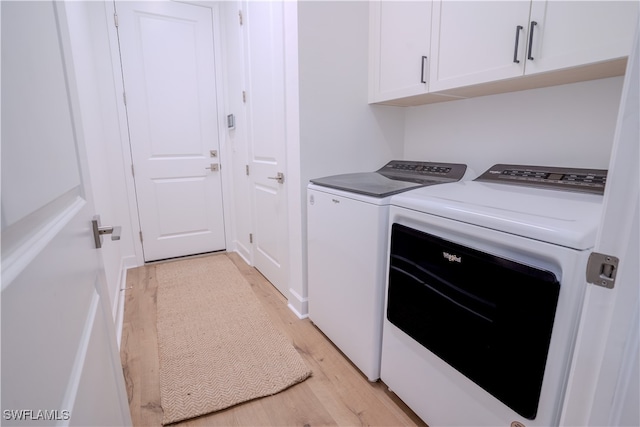 laundry area featuring cabinets, independent washer and dryer, and light hardwood / wood-style flooring