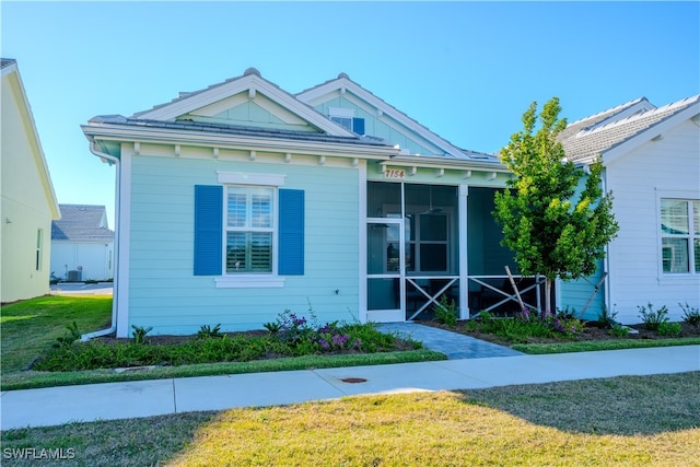 view of front of property featuring a sunroom and a front lawn