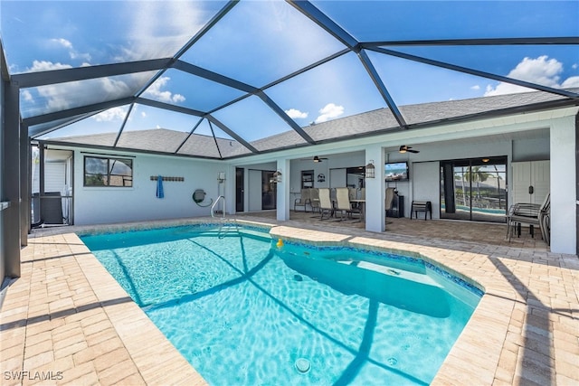 view of swimming pool featuring glass enclosure, a patio, and ceiling fan