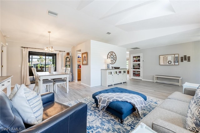 living room featuring light hardwood / wood-style floors, a notable chandelier, and lofted ceiling