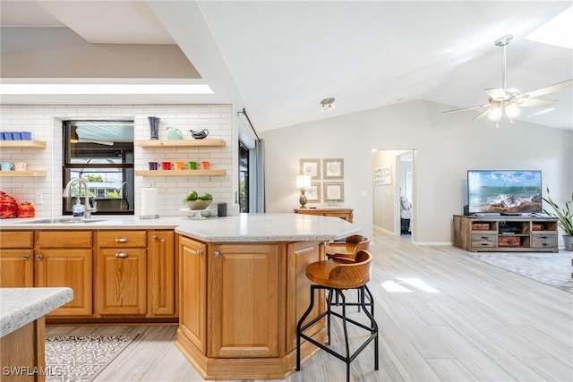 kitchen with a kitchen bar, light wood-type flooring, lofted ceiling, and backsplash