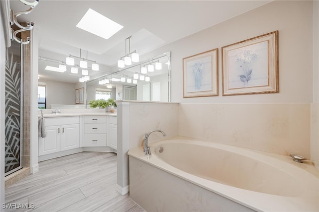 bathroom with wood-type flooring, vanity, a bathtub, and a skylight