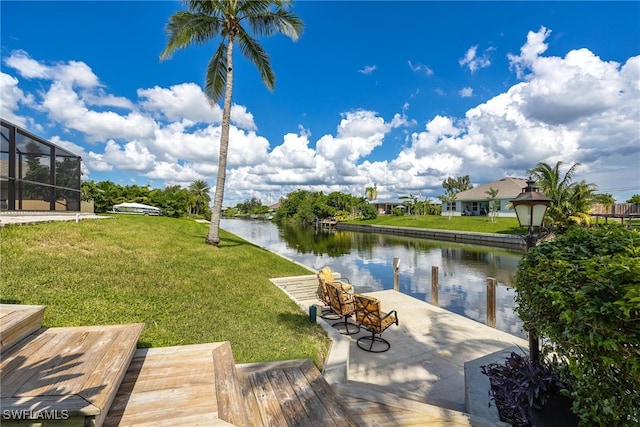 view of dock with a lanai, a yard, and a water view