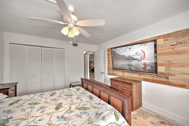 bedroom with a closet, light wood-type flooring, wooden walls, and ceiling fan