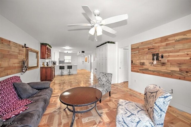 living room with ceiling fan, a barn door, and light parquet flooring