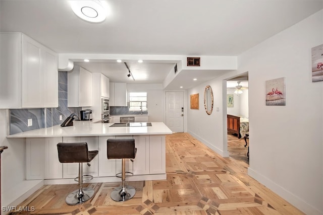 kitchen featuring kitchen peninsula, a breakfast bar area, and white cabinetry