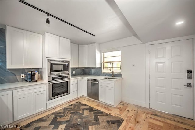 kitchen with light countertops, appliances with stainless steel finishes, a sink, and white cabinets