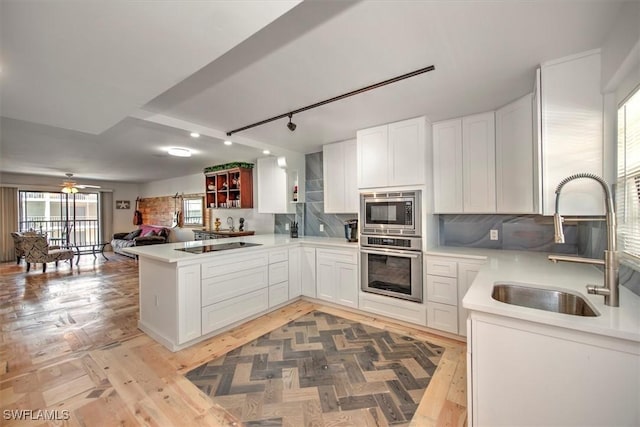 kitchen featuring white cabinets, open floor plan, a sink, stainless steel appliances, and backsplash