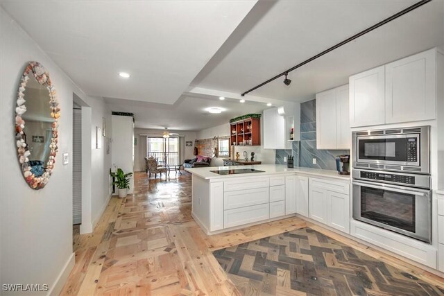 kitchen featuring stainless steel appliances, kitchen peninsula, tasteful backsplash, and white cabinetry