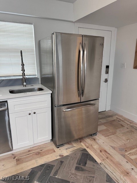 kitchen with white cabinets, light hardwood / wood-style floors, appliances with stainless steel finishes, and sink