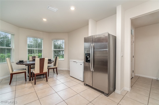 kitchen featuring light tile patterned flooring, fridge, and stainless steel refrigerator with ice dispenser