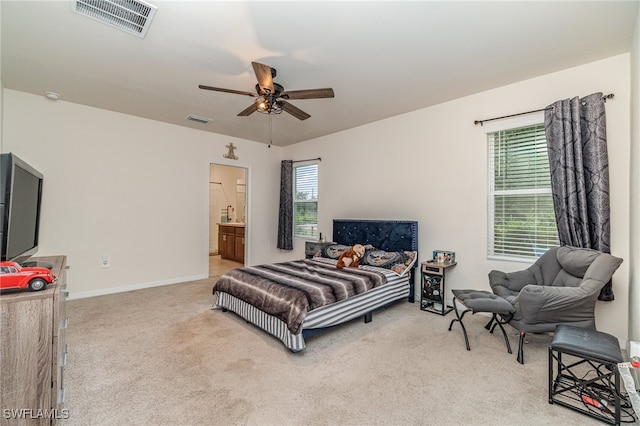 carpeted bedroom with ensuite bath and ceiling fan